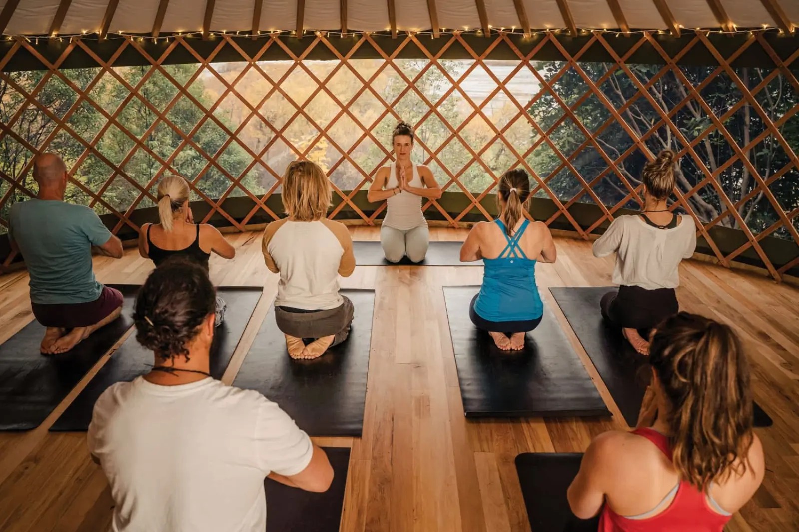 Woman leading a yoga group inside a wooden yurt at Kinloch Lodge Wilderness Retreat.