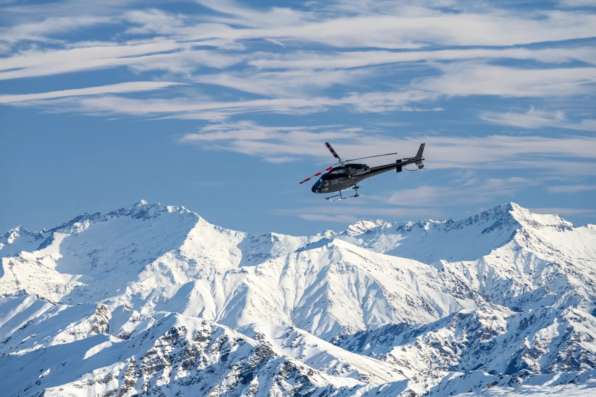 Helicopter flying down towards a snowy mountain range.