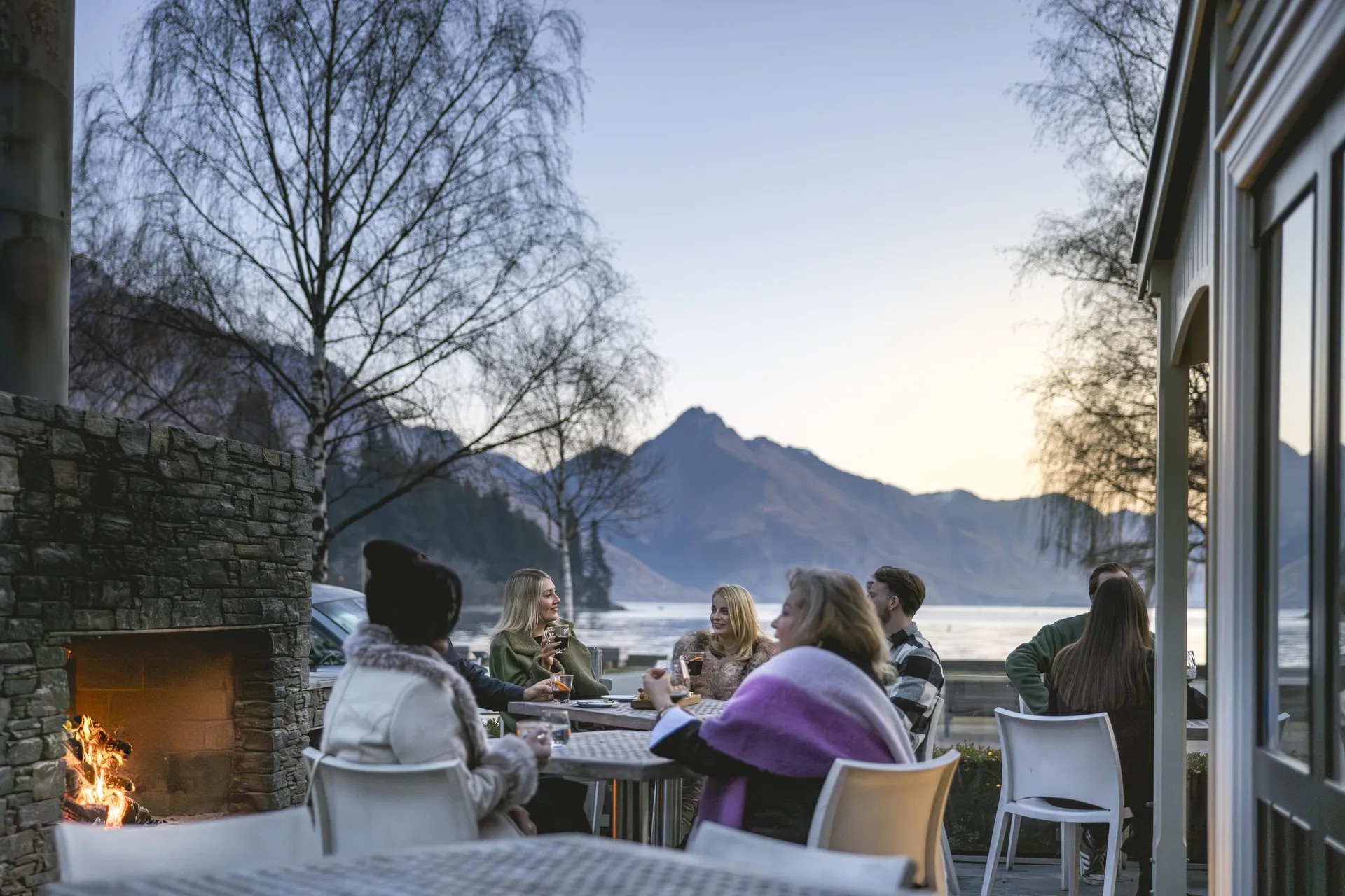 Group dining outside Botswana Butchery with view of Lake Wakatipu and surrounding mountains in distance.