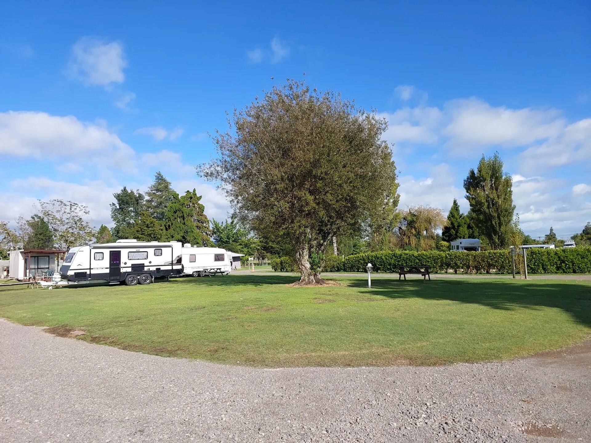 Camping ground featuring recreational vehicles parked on green sites with established trees and spacious grounds.