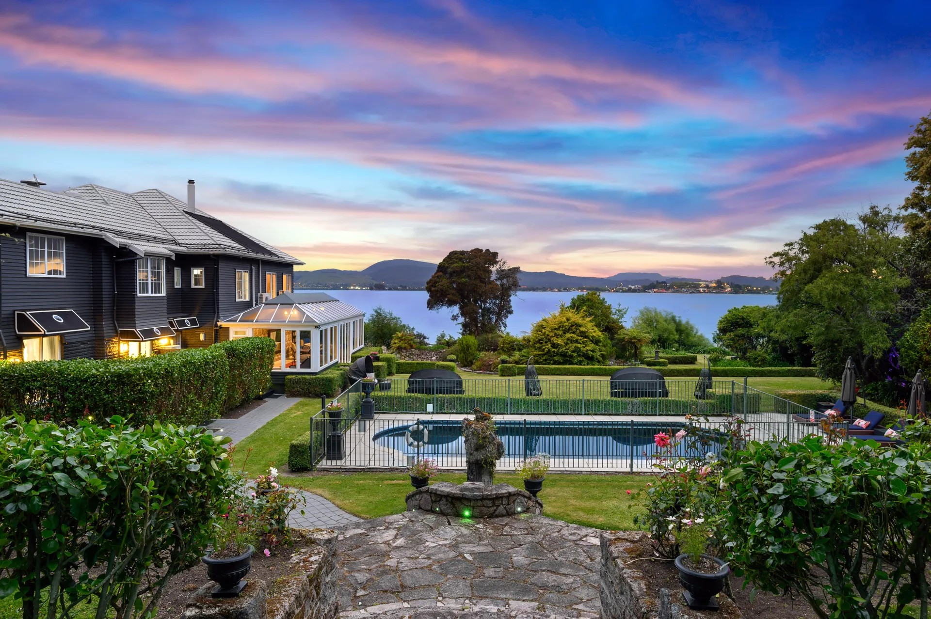 Black Swan Lakeside Boutique Hotel pool area with sunset views over lake, landscaped gardens and mountain backdrop.