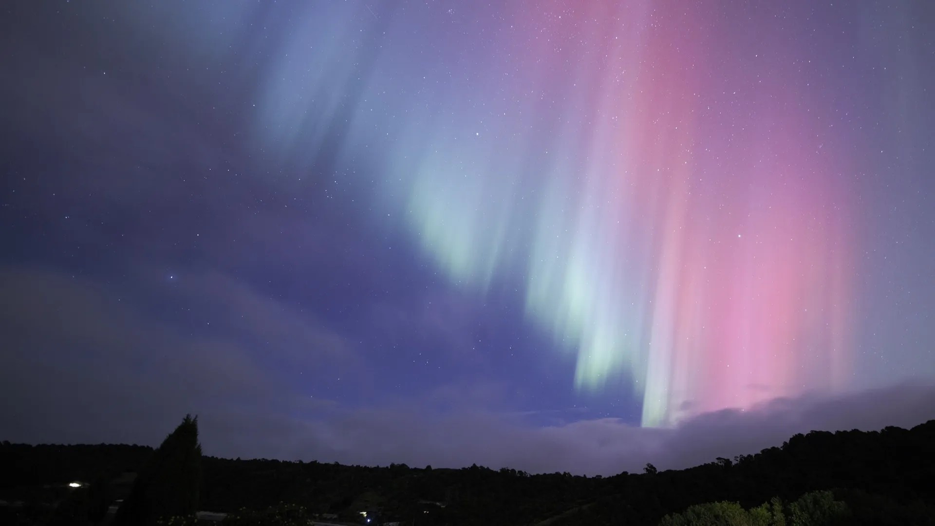 Pink-blue aurora over Stewart Island at night.