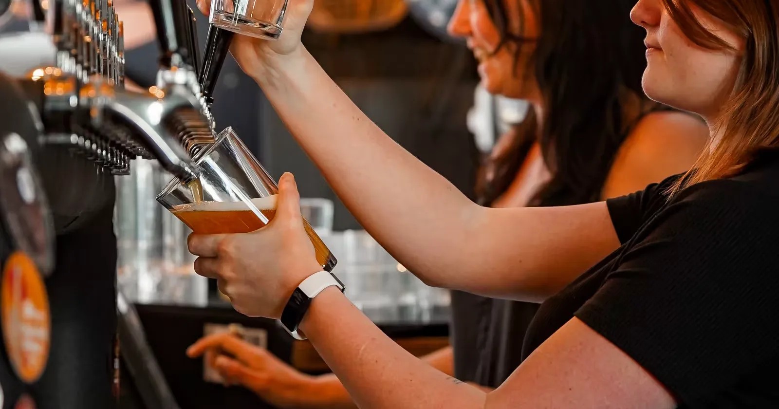 Woman filling a glass with beer at a tap at the Beech Tree Craft Beer bar.