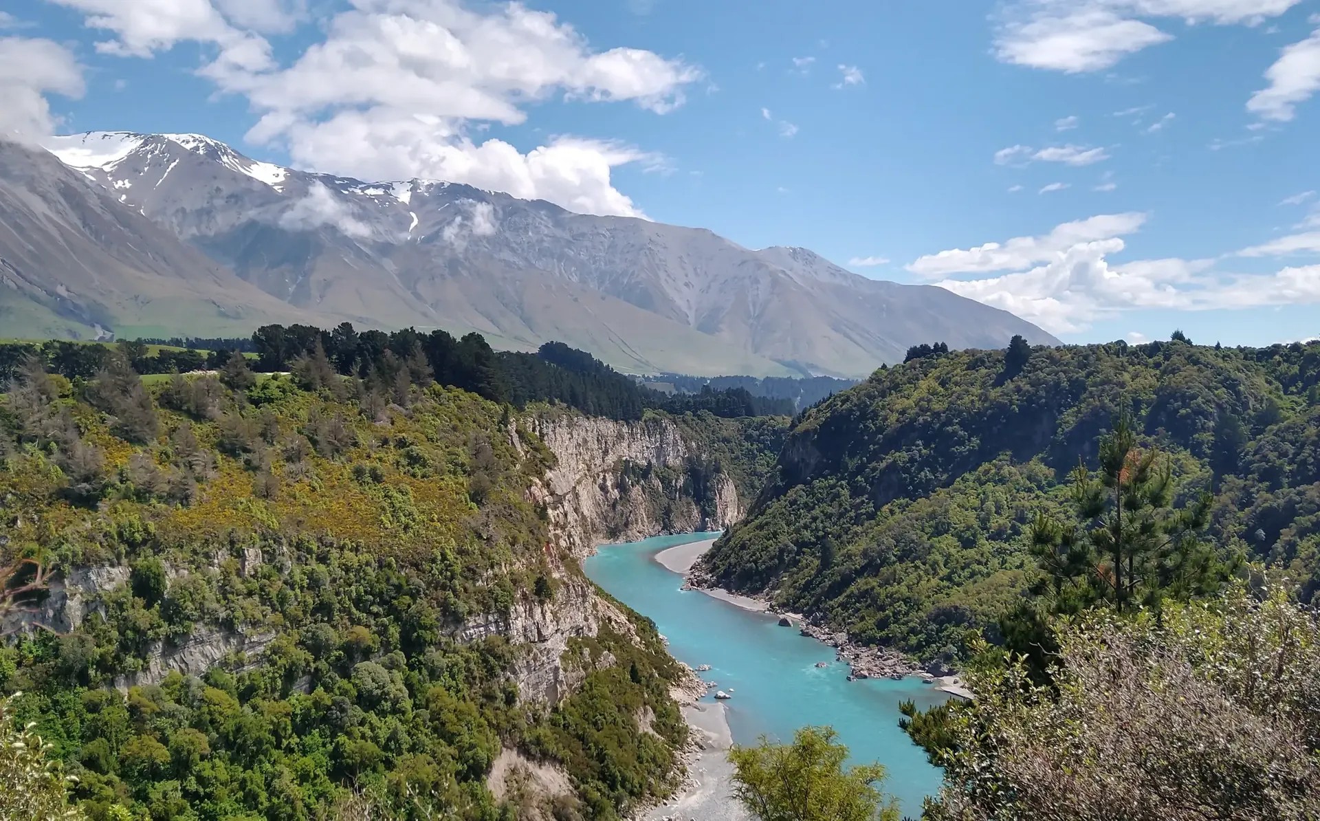 Aerial view of Rakaia Gorge showing bright blue river, steep forested cliffs and alpine peaks in Canterbury region.