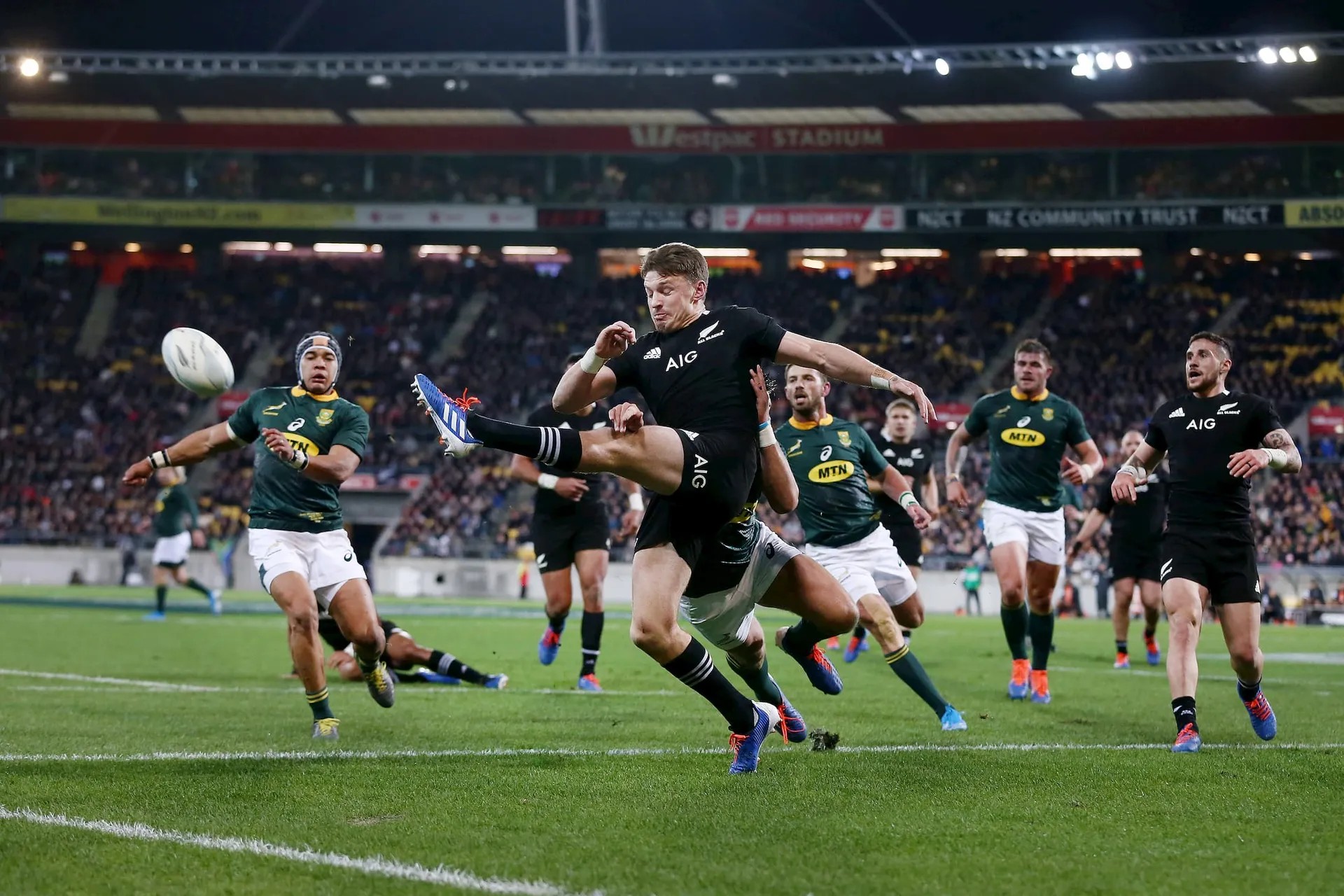 All Blacks player kicking ball during rugby match against South Africa team.