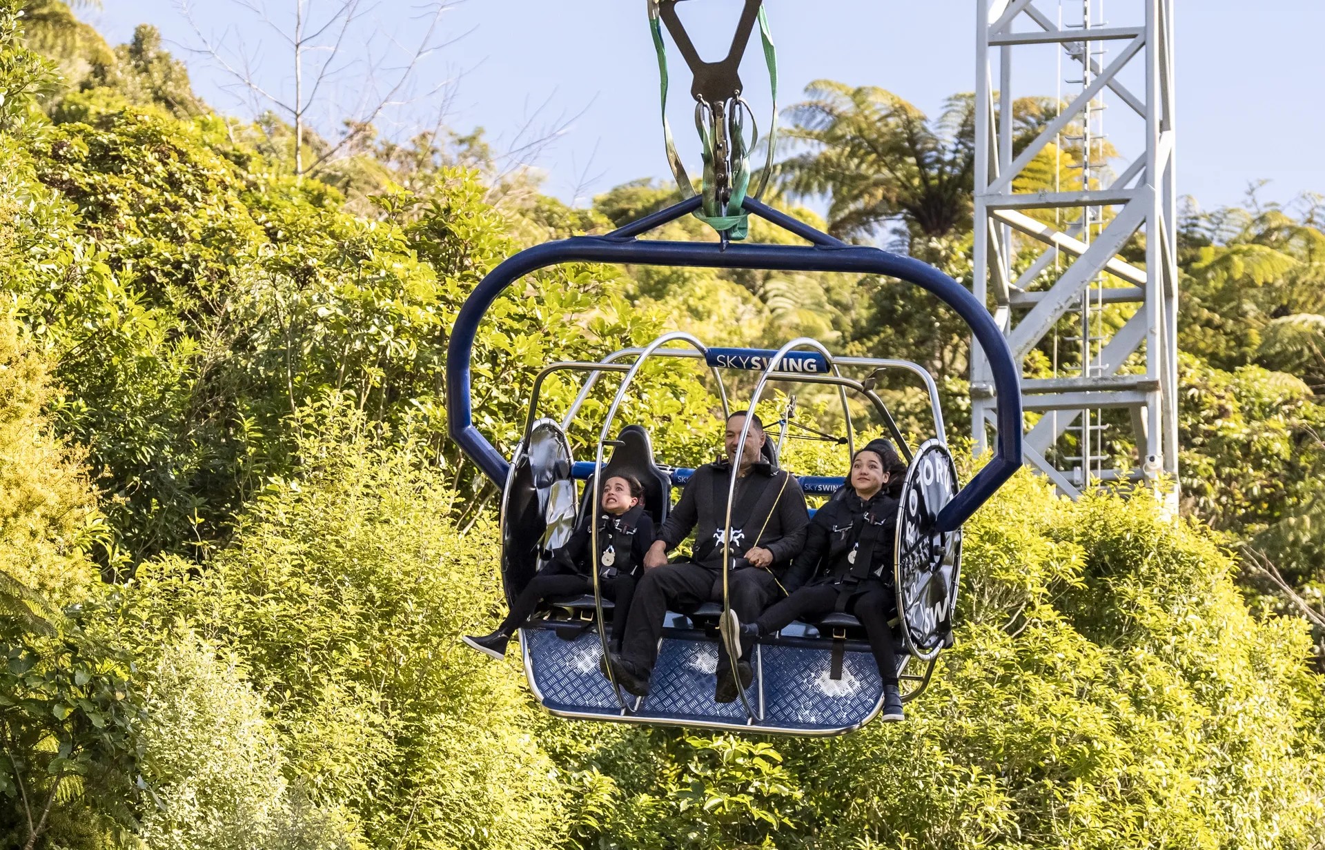 A family riding the Skyswing attraction in the air among the trees.