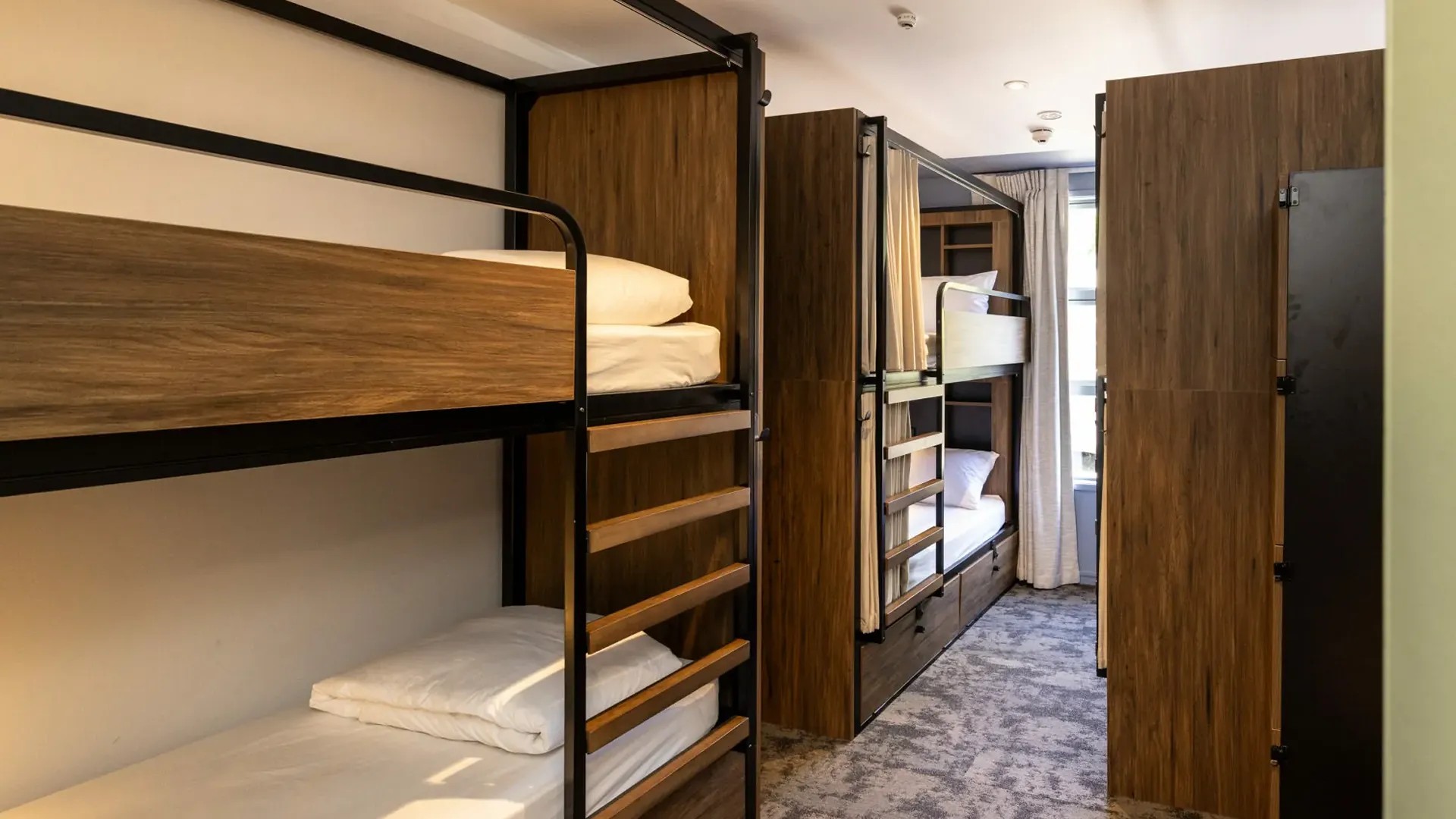 Interior of a Haka House backpacker hostel with two wooden bunk beds visible.