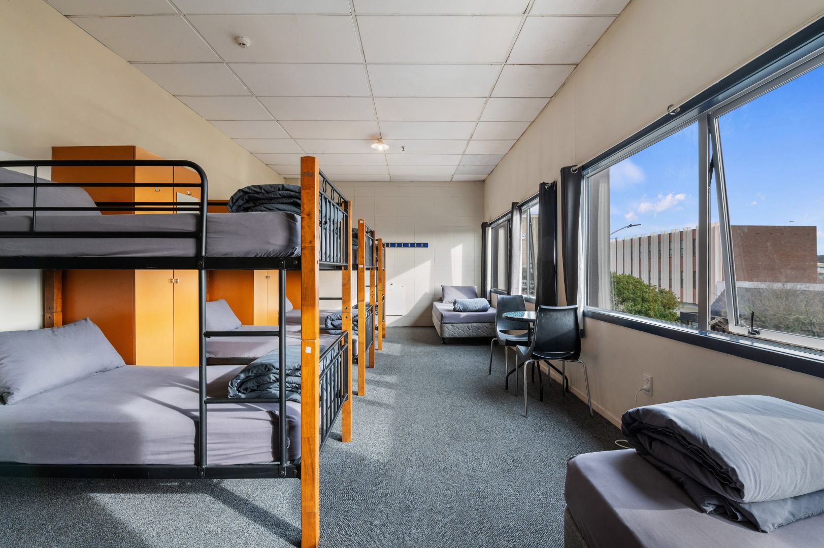 Backpacker dorm room with three bunk beds and two single beds.