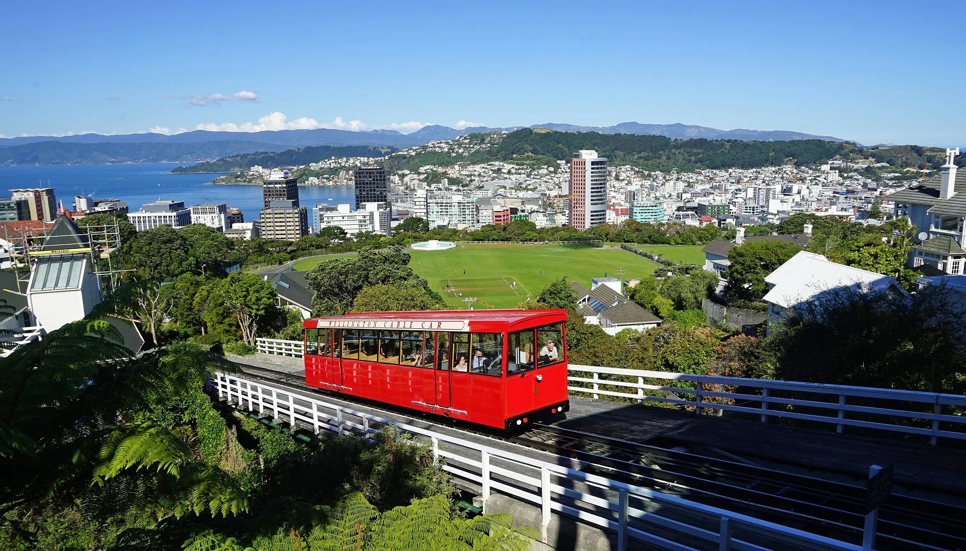 The Wellington Cable Car going up the tracks with a view of Te Aro and the bay in the background.