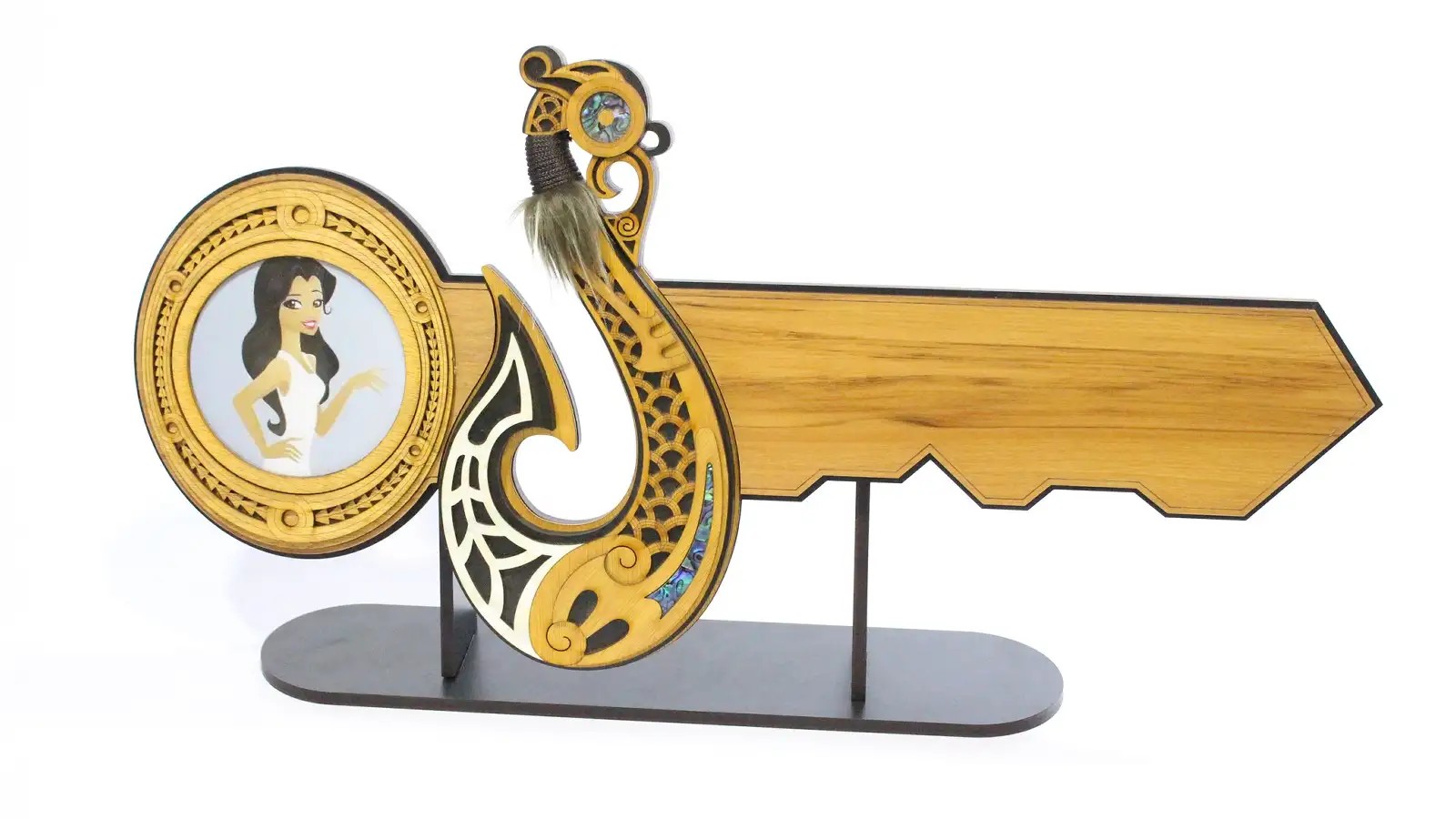 Wooden celebration key carving with Maori fishhook design in centre.