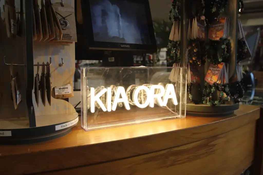 Lit up kia ora sign inside the gift shop surrounded by jewellery for sale.