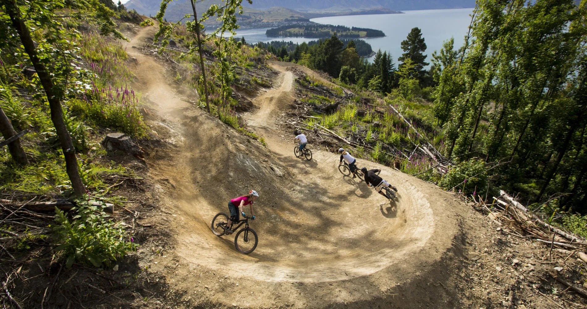 Four bikers turning a corner down a mountain biking path.