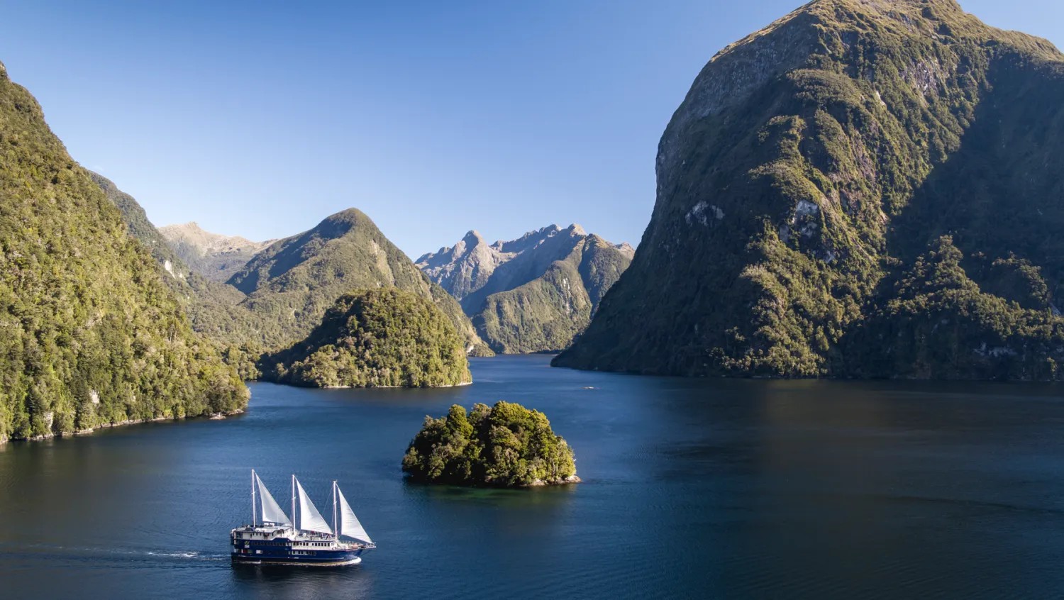 A cruise ship sails between large cliff faces.