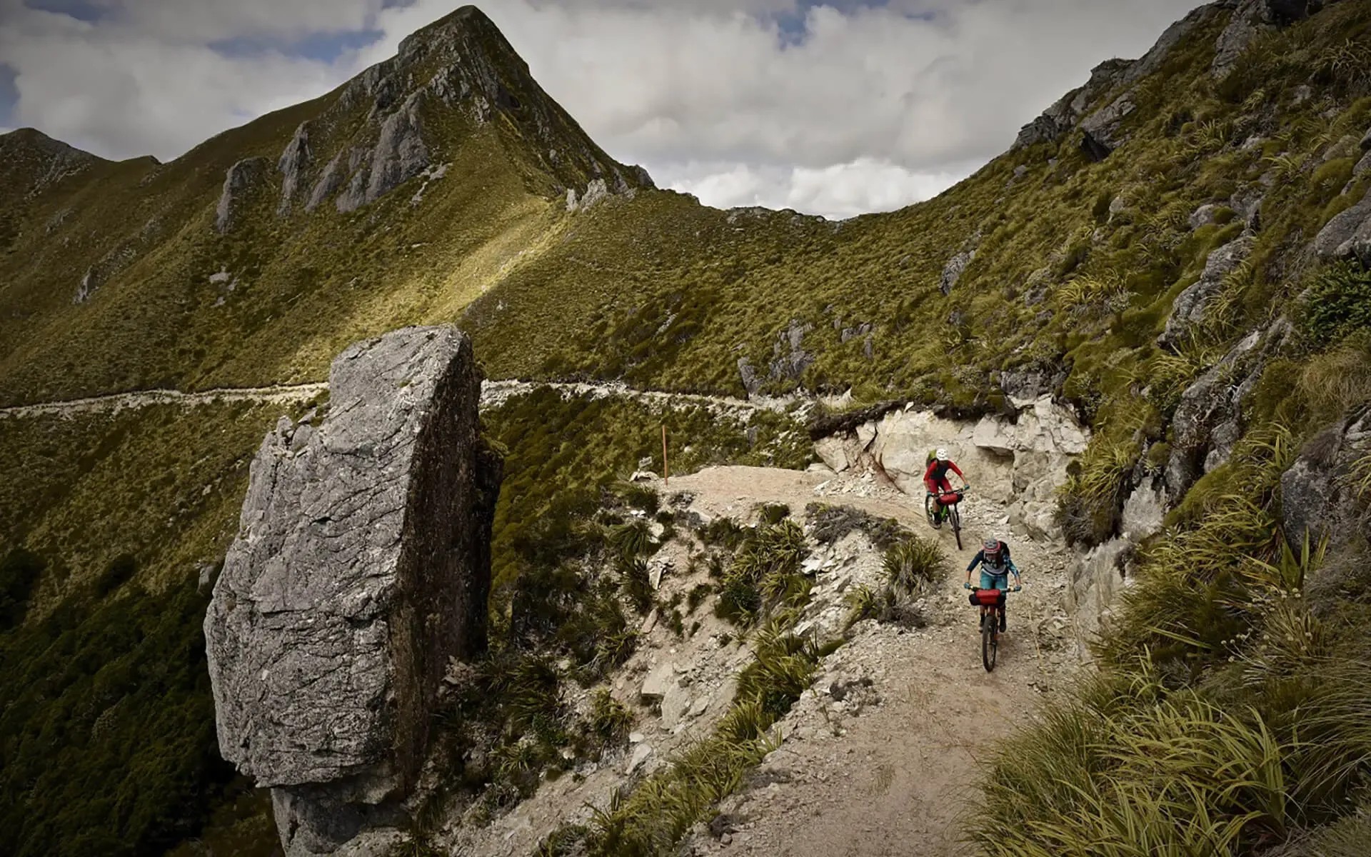 Two bikers riding a tight rocky path.