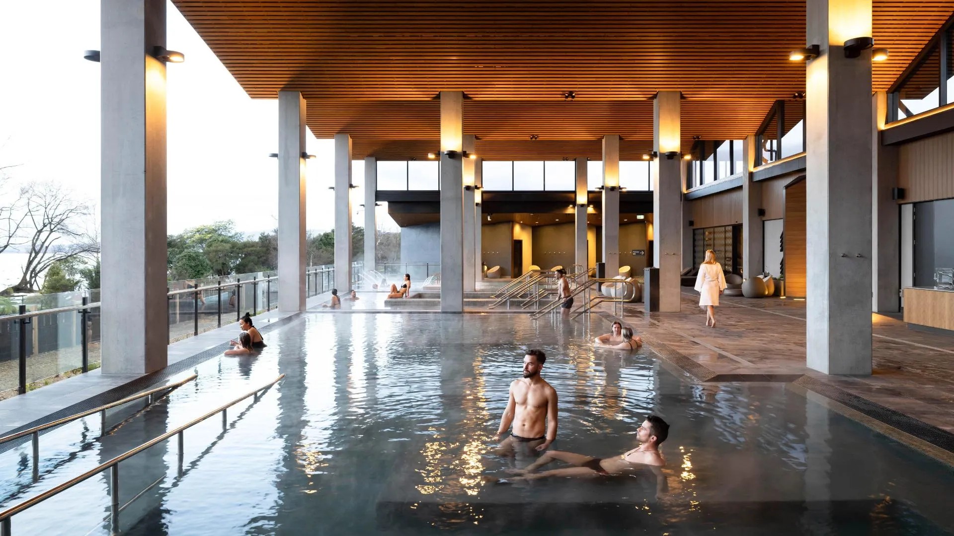 Upscale, modern concrete hot pool, various people relaxing in the water.