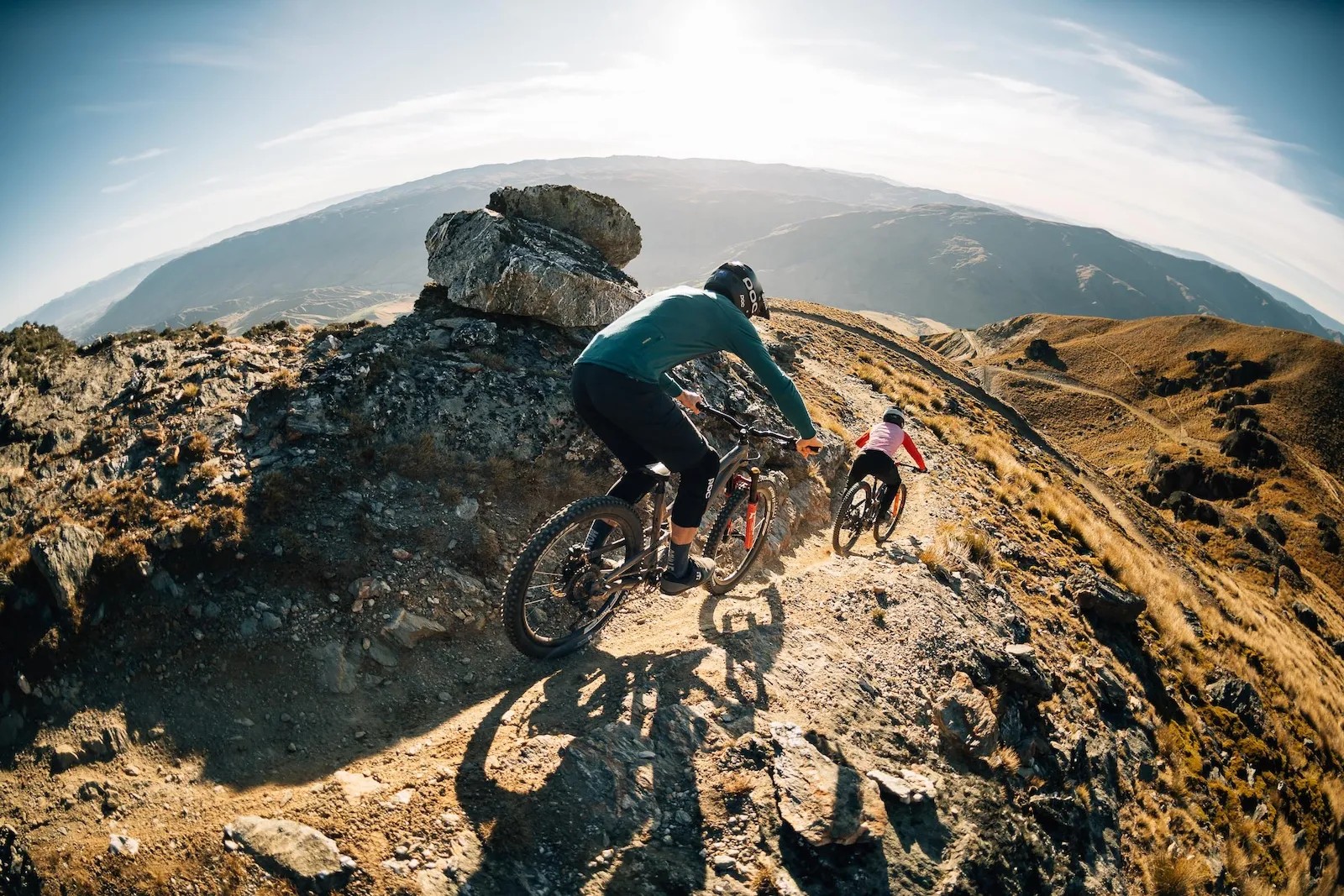Bikers riding down a rocky mountain path.