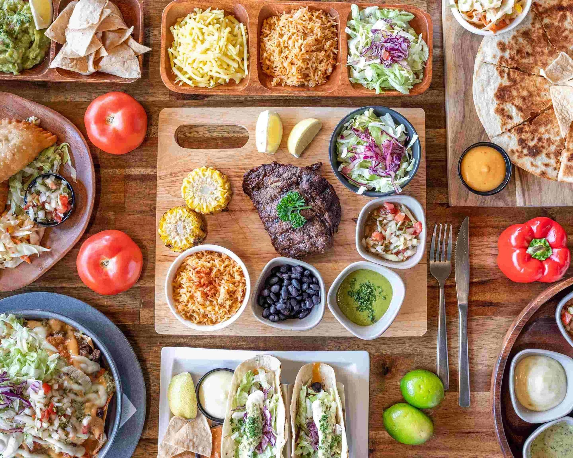 Top-down view of a large assortment of Mexican food on wooden platters.