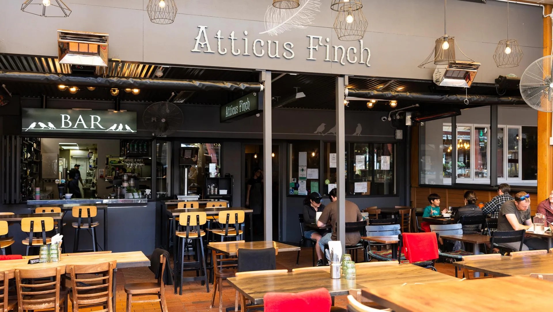 Exterior of the Atticus Finch restaurant and bar with families and couples eating at tables.
