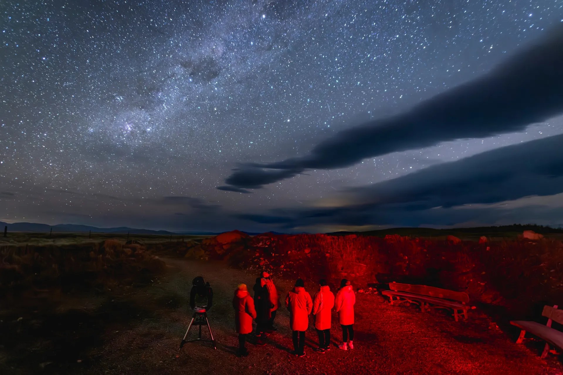 Group looking at starry sky, ground lit red off-camera.