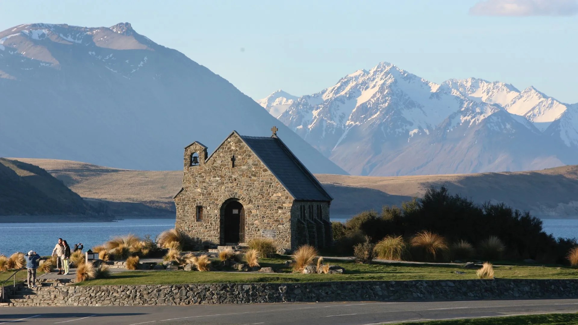 Stone church set against Lake Tekapo and snowy mountains.