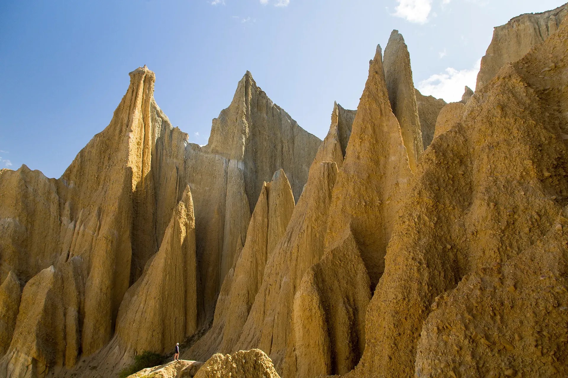 Person looking up at giant beige clay cliffs.