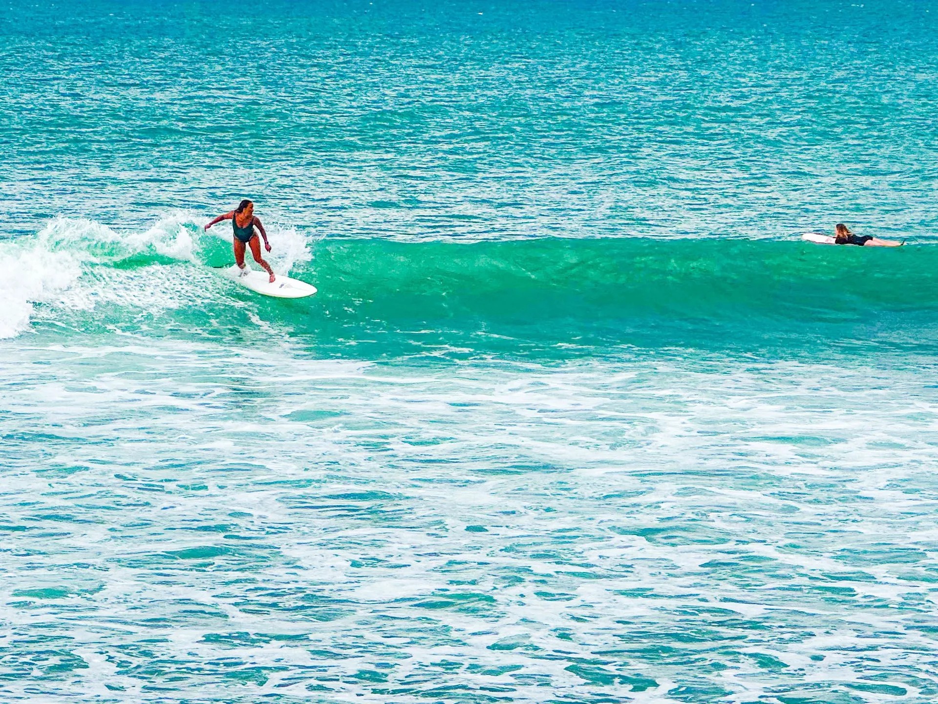 Person surfing on a wave in clear turquoise waters.