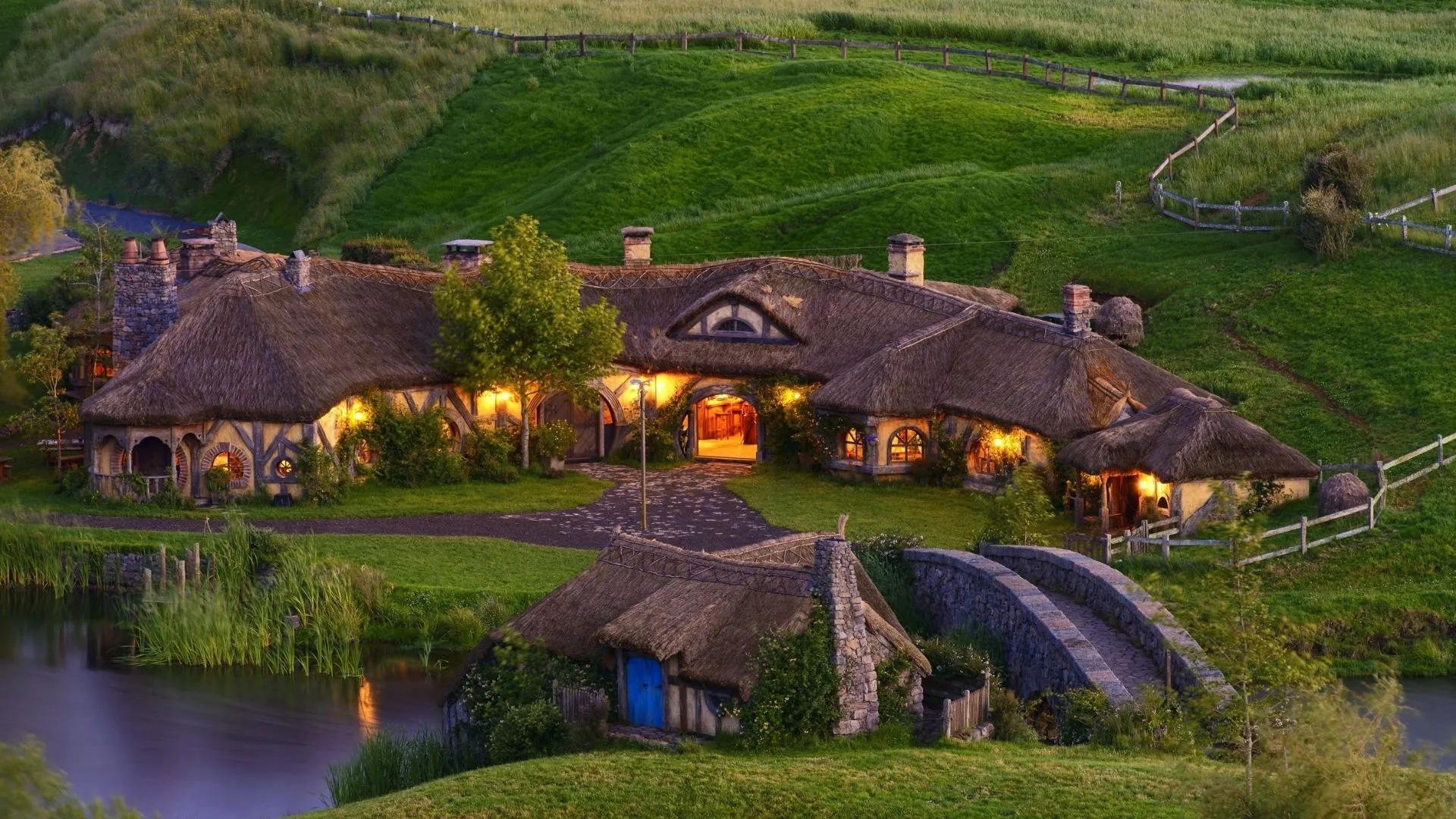 Medieval thatched roof buildings on a grassy hill.