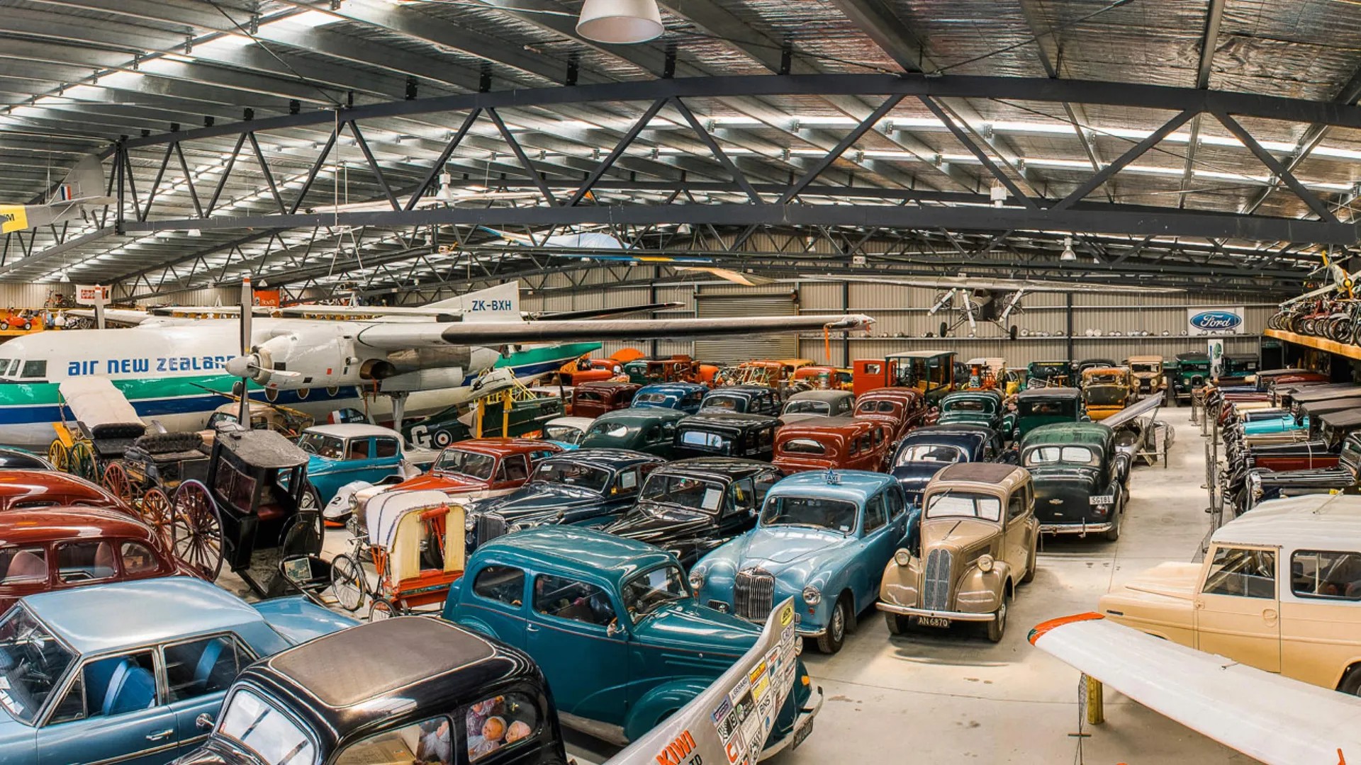 Large hangar filled with vintage cars and planes.