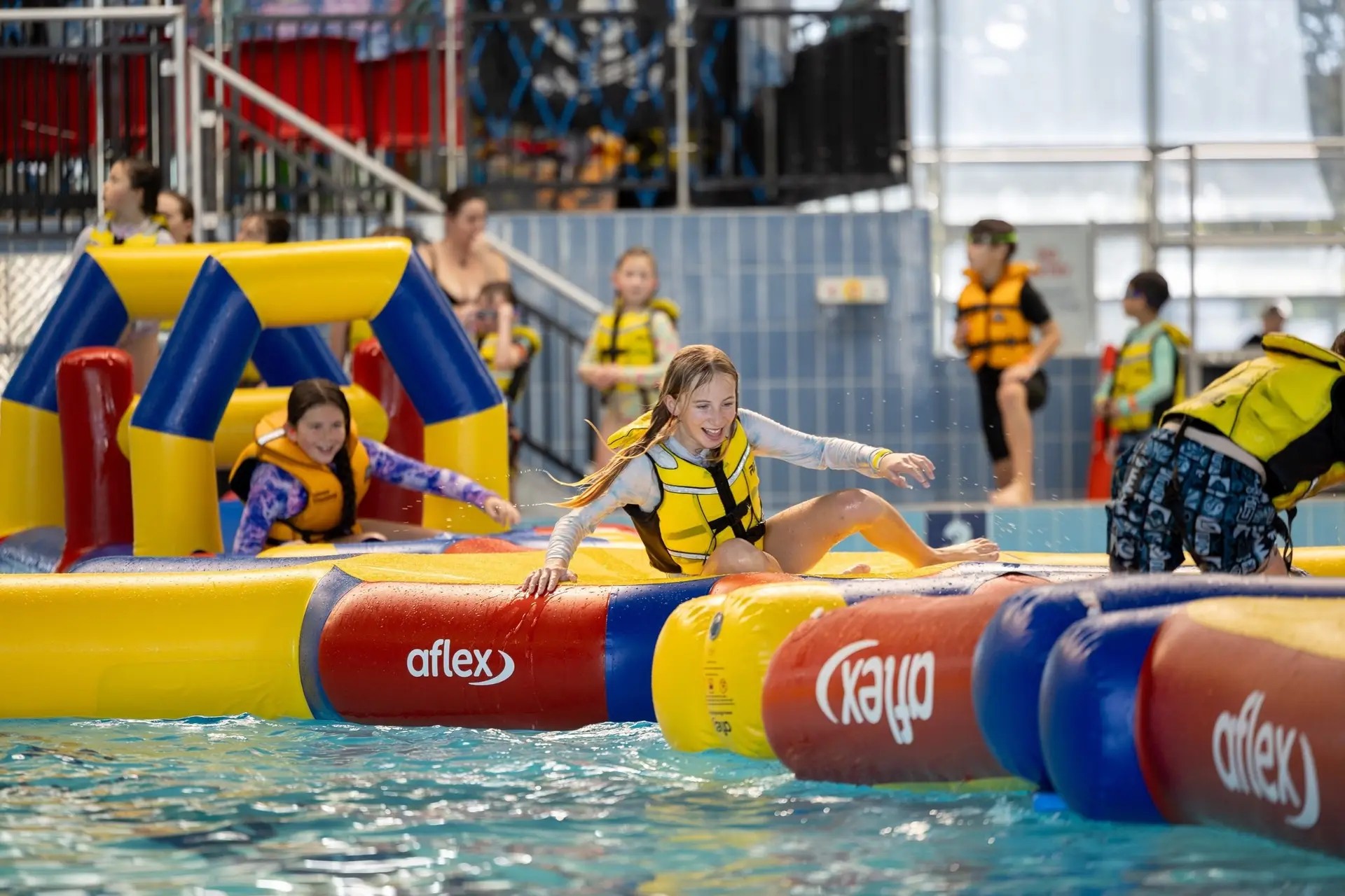 Kids playing on an inflatable adventure course in a water park.