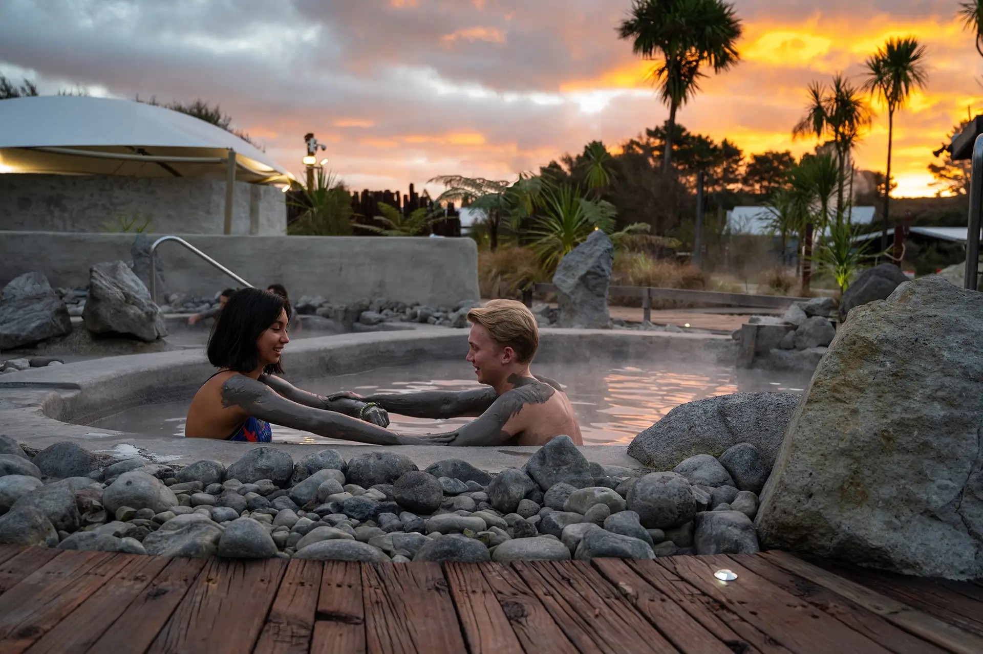 A couple lathers mud onto each other in a Hells Gate mud pool.