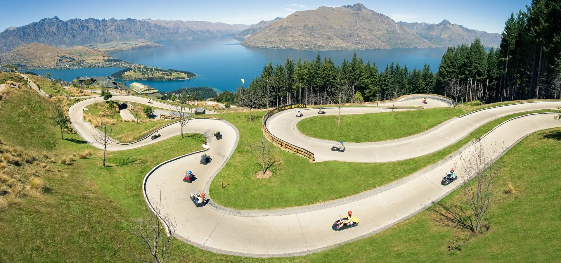 People racing down a winding Luge path at Skyline Queenstown.