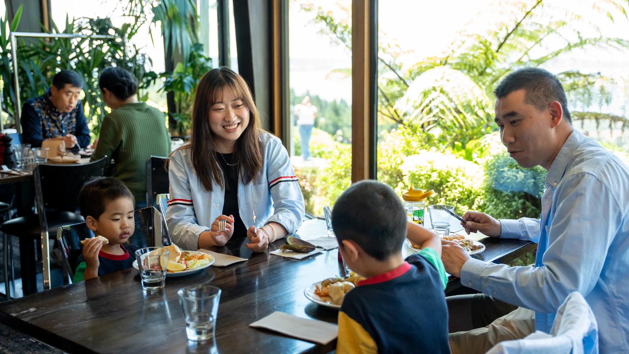 Family enjoying lunch together at Stratosfare Restaurant with scenic views at Skyline Rotorua.