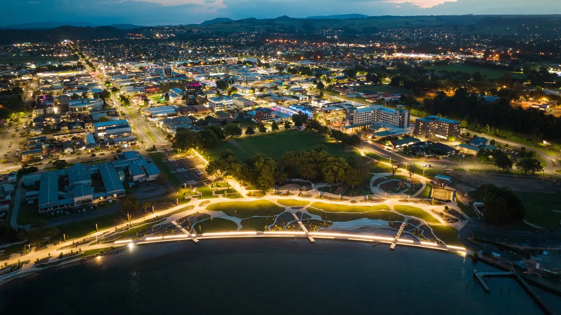 Aerial view of the Rotorua lakefront at night, illuminated by lights