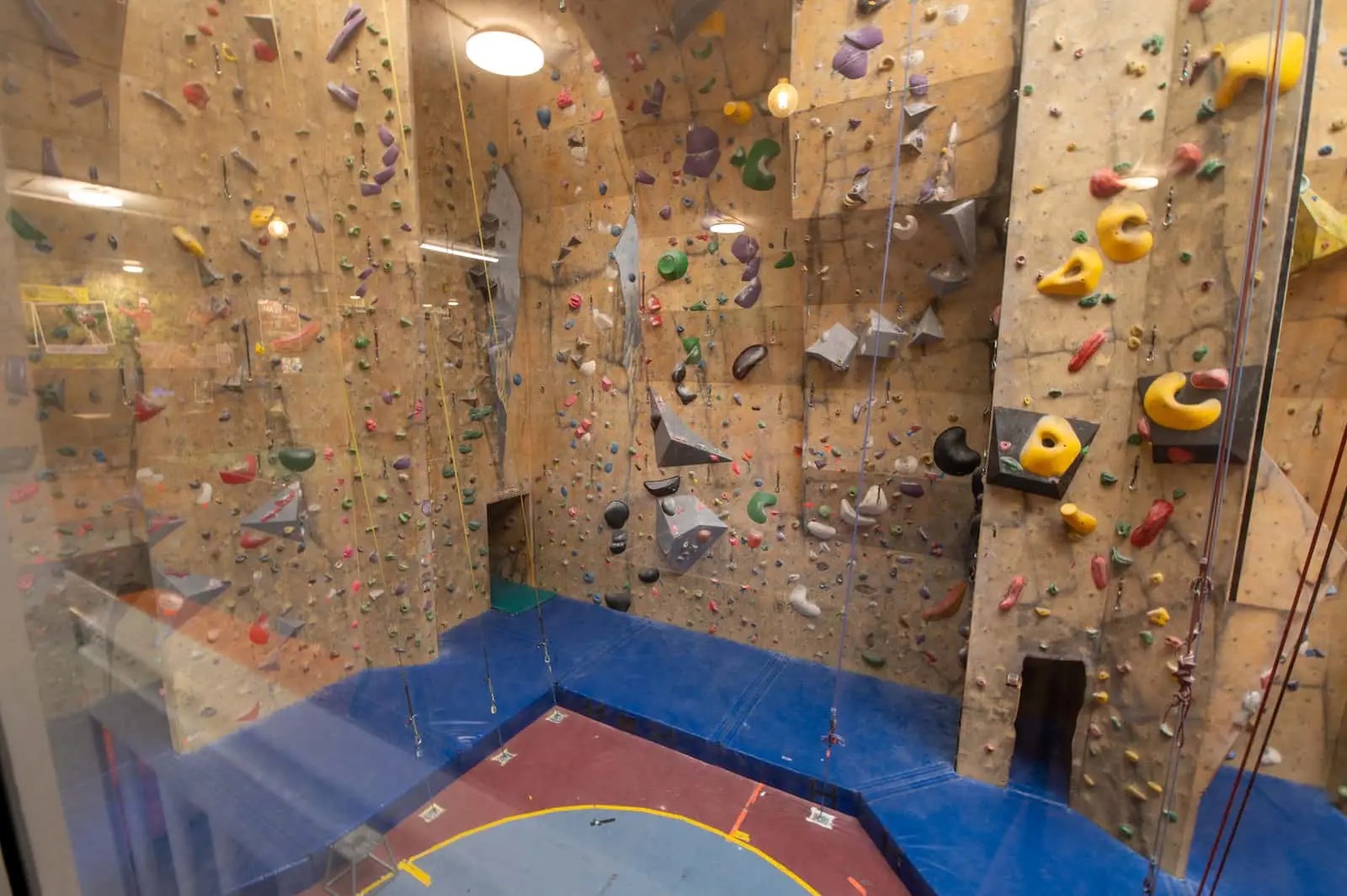 Indoor rock climbing wall with safety mats underneath.