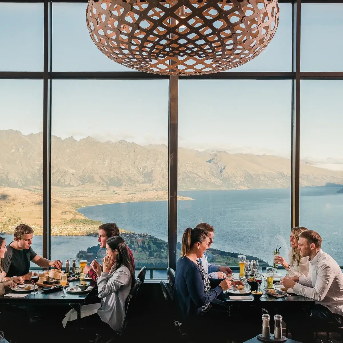 Guests dining at Skyline Stratosfare Restaurant with panoramic lake and mountain views in Queenstown
