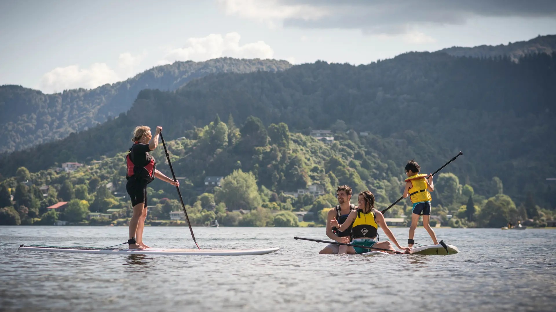 An instructor and a family paddleboarding on a lake.