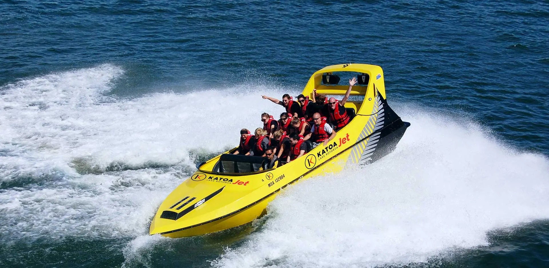 A group of people excitedly riding the Katoa Jet jet board on Lake Rotorua.