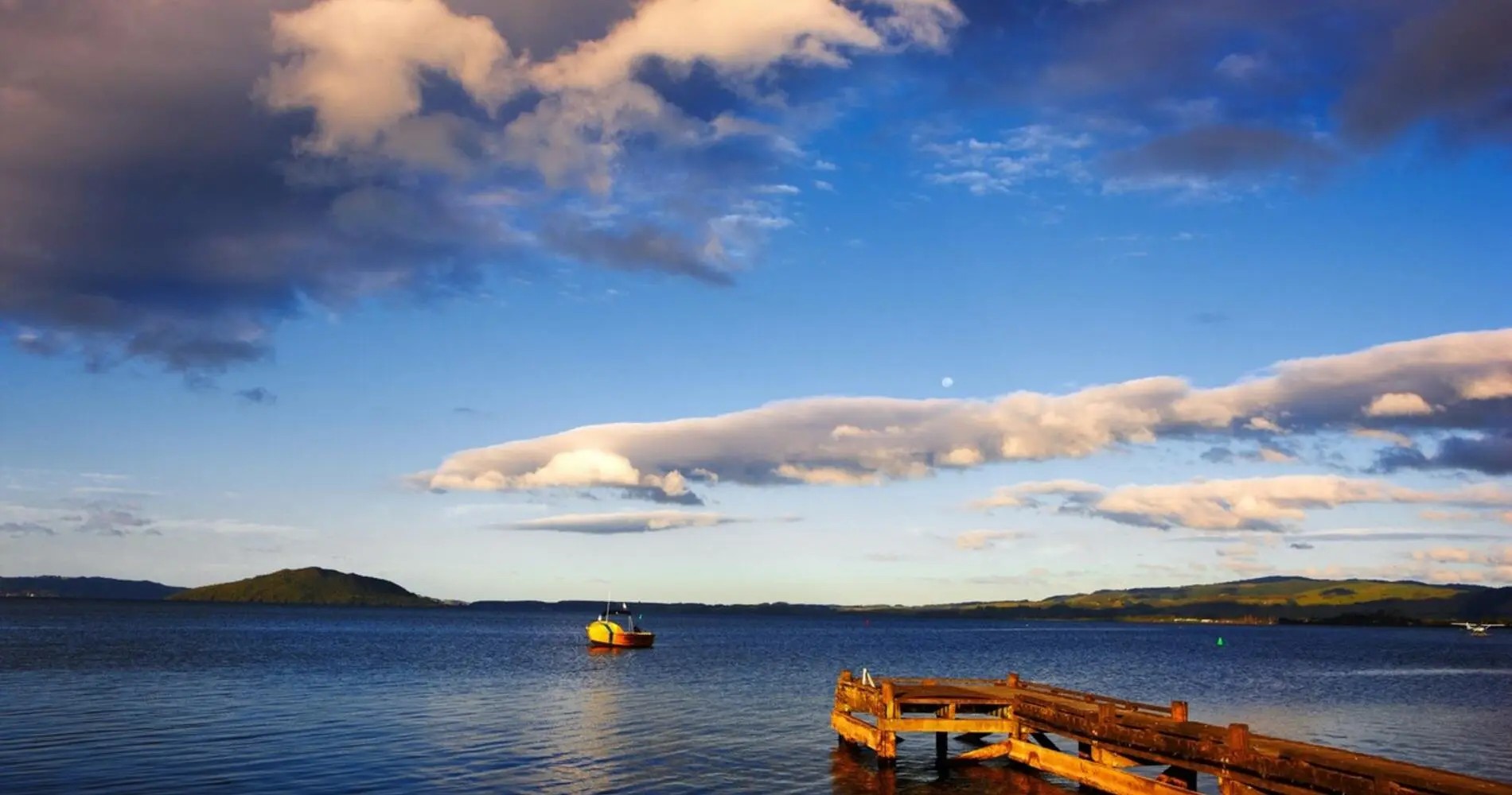 A wooden boat jetty on Lake Rotorua, with a small boat off in the distance.