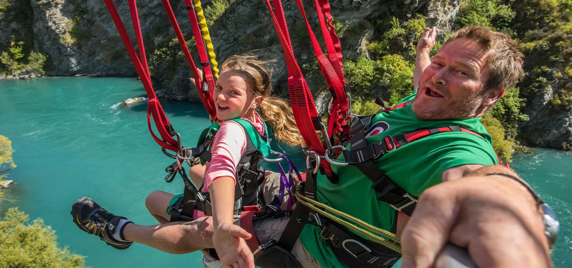 A family taking a selfie over the Kawarau River while riding a zipline.