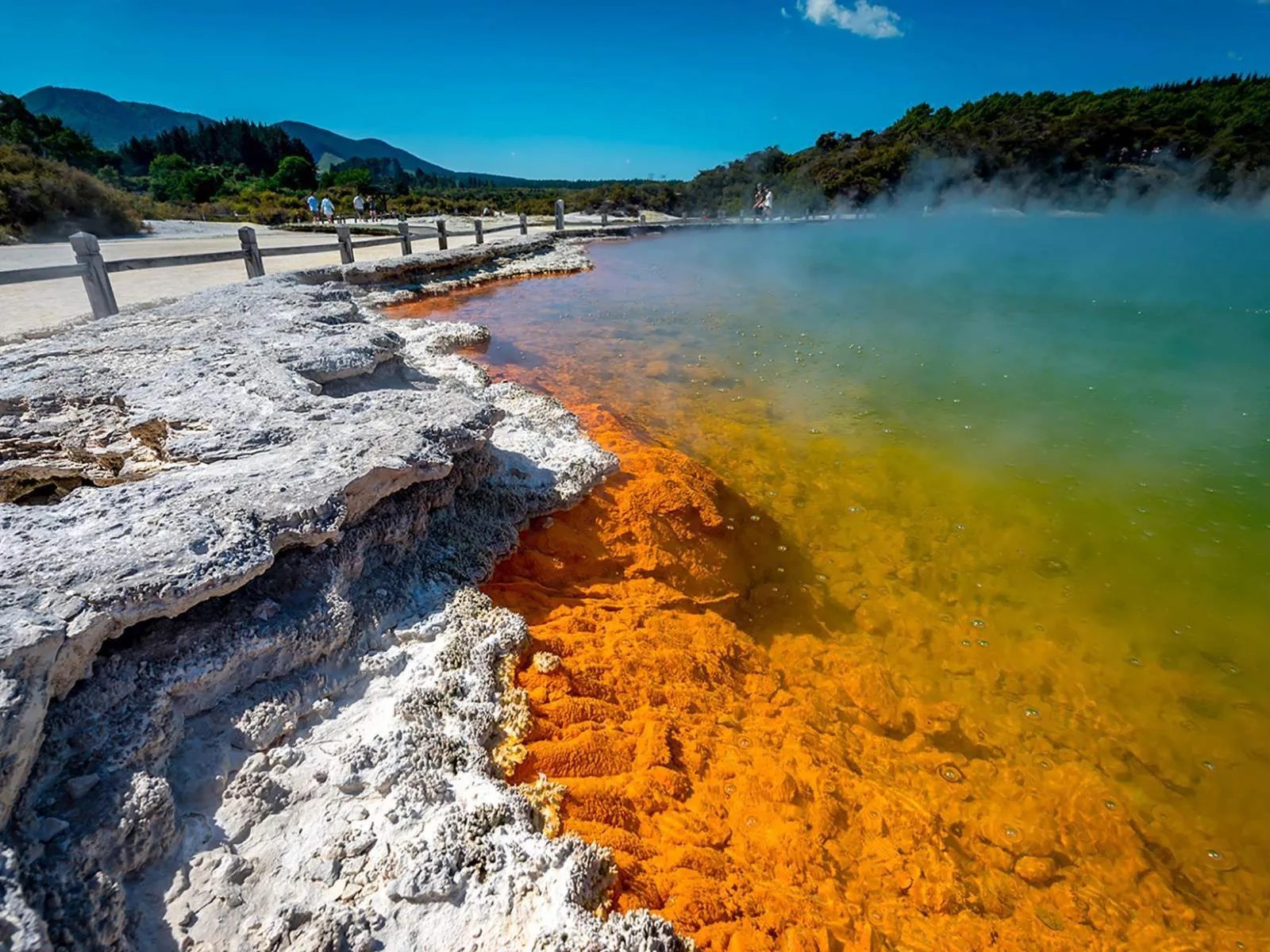 Geothermal pool filled with steaming turquoise-orange water.