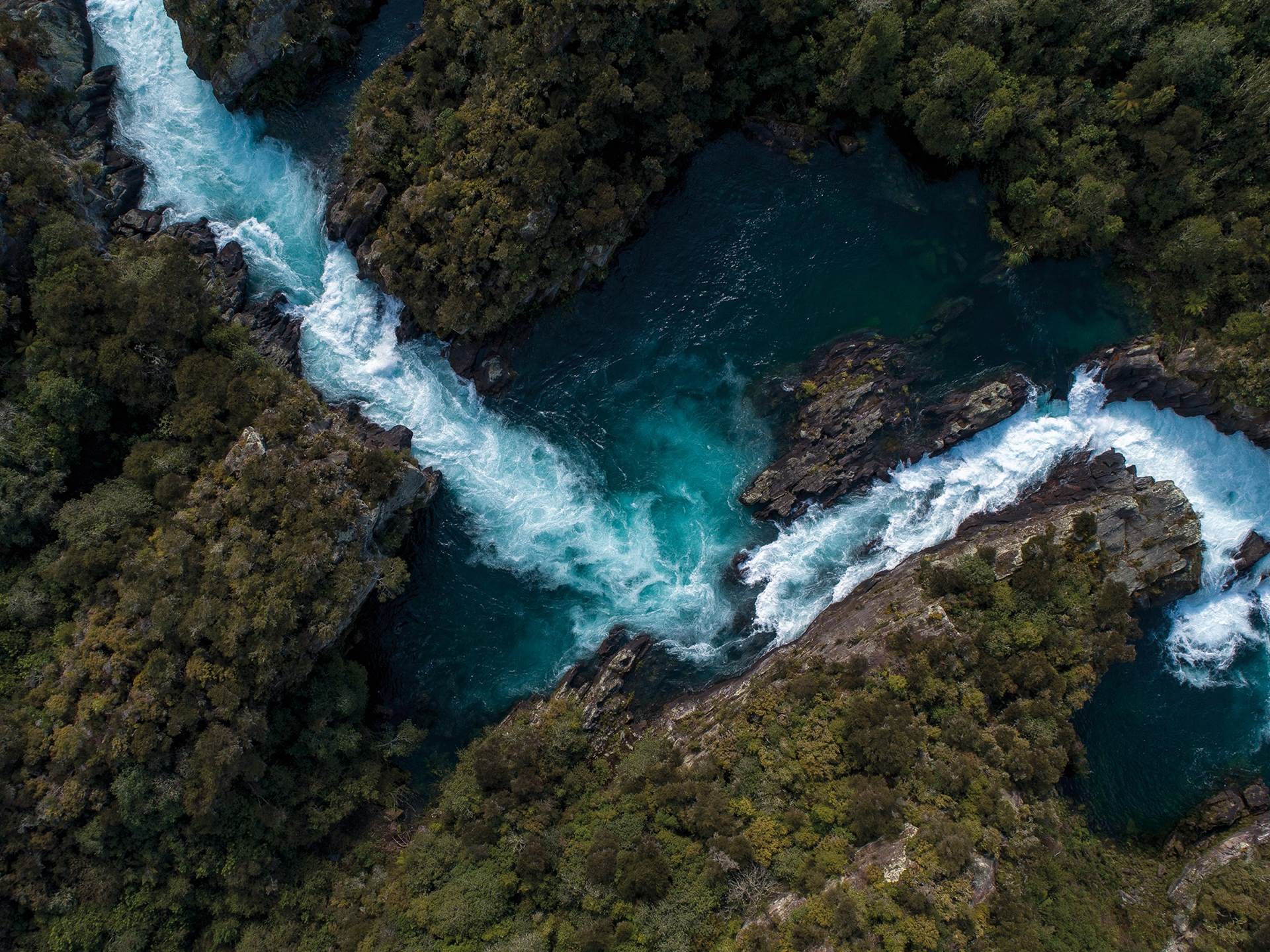 Turquoise river between high rocks; white rapids gushing down.