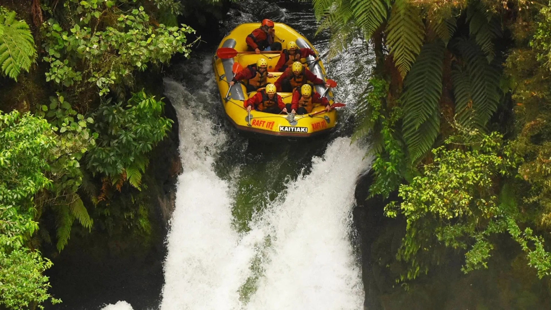 A group of people in an inflatable raft, about to go down river rapids